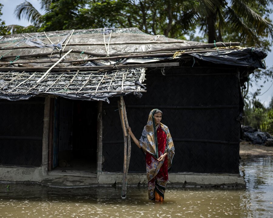 A woman stands in flood waters in front of her home